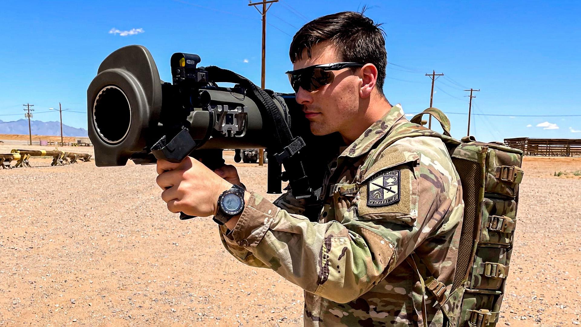 cadet holding large weapon on sandy terrain